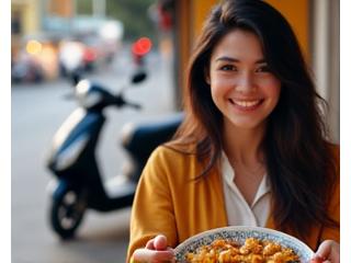 Woman enjoying street food from a vendor cart, with a scooter in the background